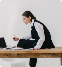 Person writing at desk with laptop
