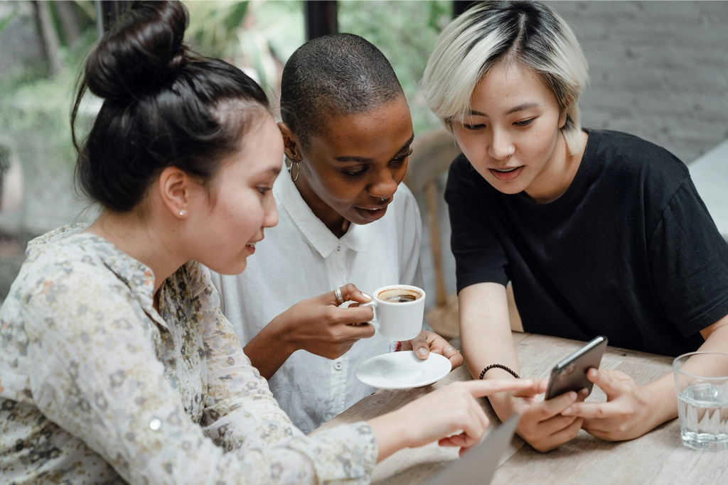 Three people discussing over coffee and phone.