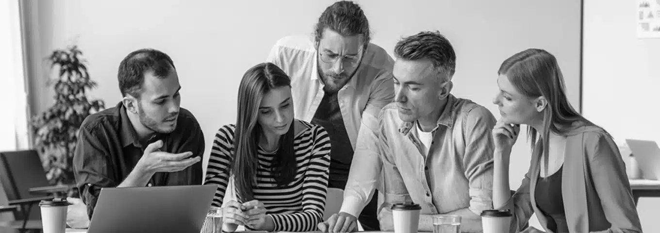 Team collaborating on a project around laptop.