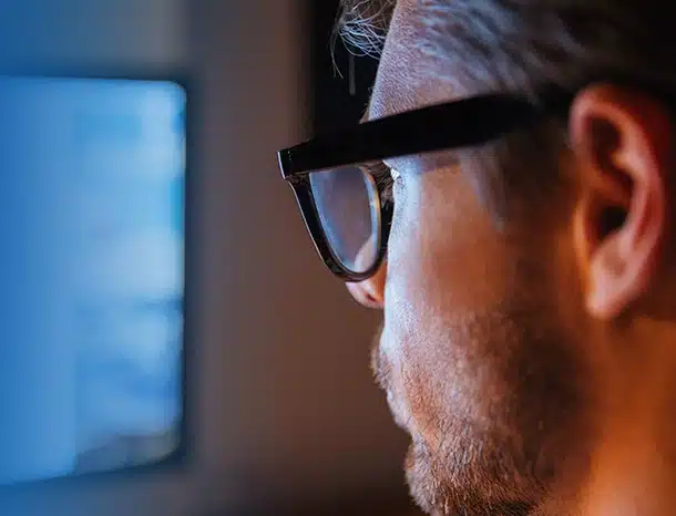 Man with glasses looking at computer screen