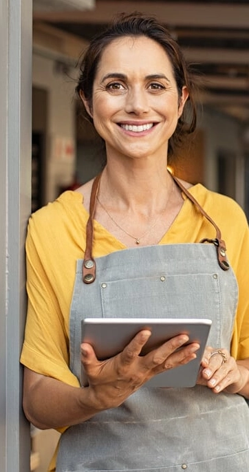 Smiling woman in apron holding a tablet