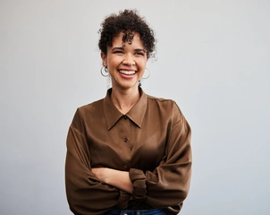 Smiling woman in brown shirt against wall
