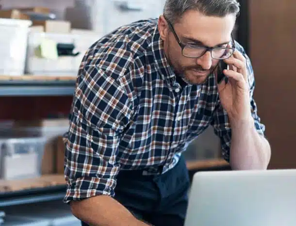 Man talking on phone while using laptop