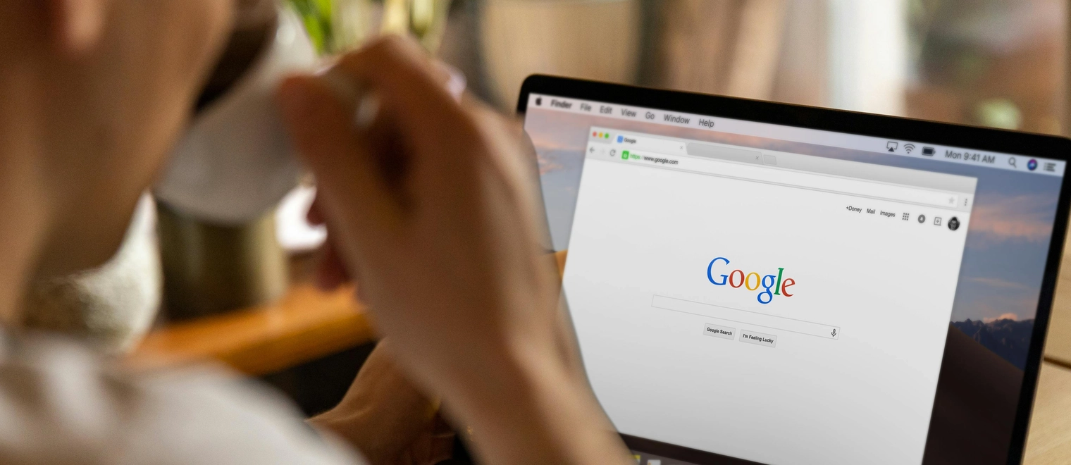 Person using laptop with Google homepage visible.